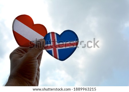 Hand holds a heart Shape Austria and Iceland flag, love between two countries
