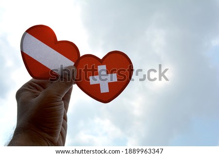 Hand holds a heart Shape Austria and Switzerland flag, love between two countries