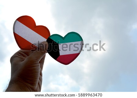 Hand holds a heart Shape Austria and Kuwait flag, love between two countries
