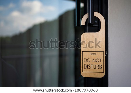 Closed door with sign PLEASE DO NOT DISTURB on handle at hotel. Royalty-Free Stock Photo #1889978968