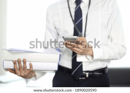 Businessman reviewing paperwork with smartphone

