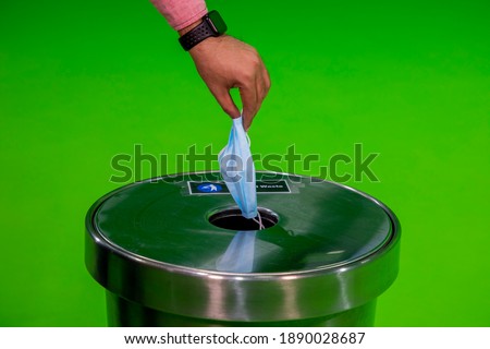Medical mask dumping in to trash can in chroma studio, green screen background