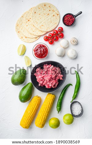 Ingredients for tacos with minced beef meat, corn tortillas, chili, avocado, over white background. Top view