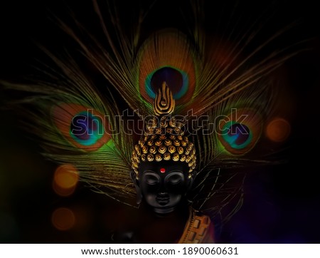 laughing buddha idol with peacock feather in the background.peaceful smiling buddha statue edited with bokeh lights.beautiful background image of buddha in calm meditated state.peaceful backgrounds
