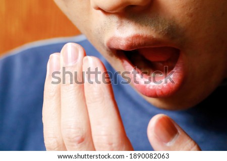 A Japanese man puts his hand in front of his mouth. Image about bad breath and yawning. Royalty-Free Stock Photo #1890082063