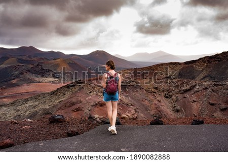 Young woman with a backpack contemplating the volcanic area Timanfaya Natural Park, in Lanzarote, travel photography