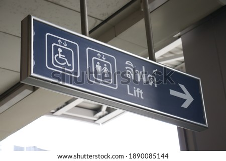 Blue sign board - Handicap elevator and icon, with Thai letter meaning : "elevator". Sky train station. Bangkok, Thailand.