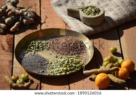 super food, chia,flax and pumpkin seeds in a traditional brass plate.tamarind,amla ginger turmatic and citrus fruits in periphery.selective focus.