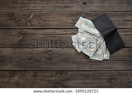 dollars in  black wallet on old wooden background