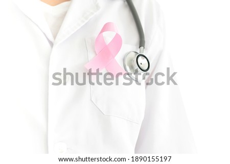 closeup of a young caucasian doctor woman with a pink ribbon for the breast cancer awareness pinned in the flap of his white coat
