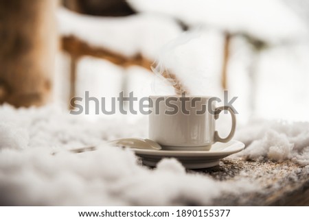 White coffee cup and saucer on a winter morning on a wooden table and fresh air. Smoke from a cup of coffee. Winter