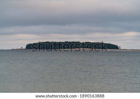 View from Neeme peninsula. Rohusi island across the sea. Nice calm Baltic Sea with no waves. Cloudy  cold winter day. Sea hasnt frozen yet and no snow. Small waves - usual for out local sea