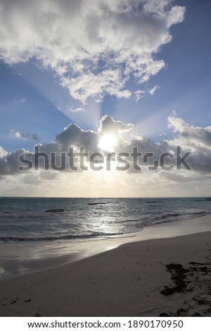 Beautiful seascape - sun rays through clouds on the coast in summer
