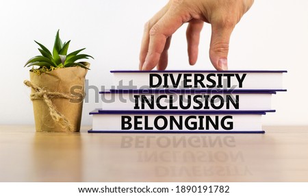 Diversity, equality and inclusion symbol. Books with words 'diversity, equality and inclusion' on beautiful white background. Male hand, house plant. Diversity, business, equality and inclusion concep