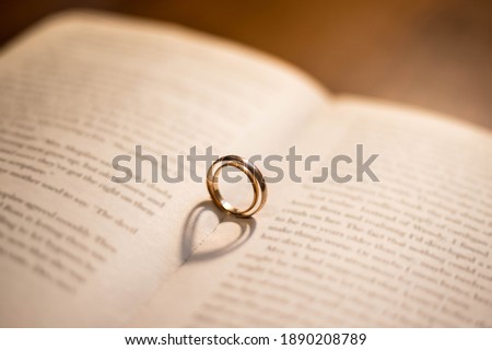 Two wedding Ring on the bible with shadow of heart shape on the open page. Engagement, wedding and nuptials. Marriage. A vow of love. Royalty-Free Stock Photo #1890208789