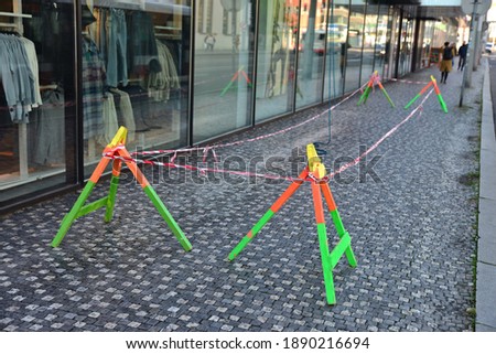 A confined space under climbers who wash the windows of an office building. Barrier against entering part of the sidewalk. Traffic safety barrier. Be careful working at heights above you.