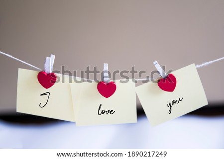 sticky notes hanging on strings and heart-shaped paper clips. I love you words Royalty-Free Stock Photo #1890217249
