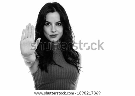 Studio shot of young beautiful Spanish woman with stop hand gesture