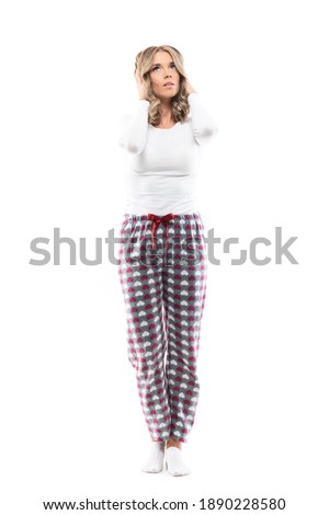 Beauty girl in pajamas touching head suffer from headache looking up sad. Full body length isolated on white background. 