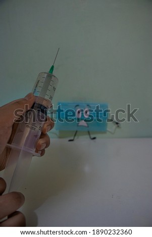 mask running away from covid-19 vaccine, trapped, hands holding syringe with pastel background color.