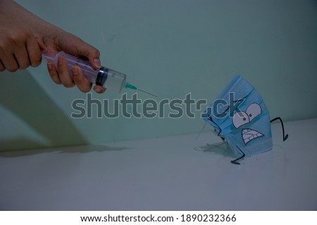 mask running away from covid-19 vaccine, trapped, hands holding syringe with pastel background color.