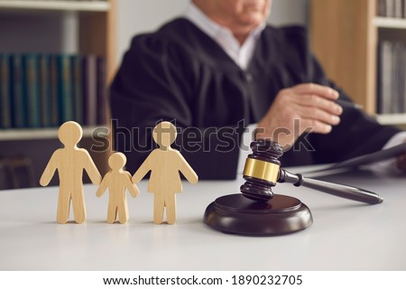 Gavel, sound block and small wooden figurines of husband, wife and kid on judge's table in courthouse during court hearing. Family law, divorce lawyer, joint custody of child and alimony concept Royalty-Free Stock Photo #1890232705