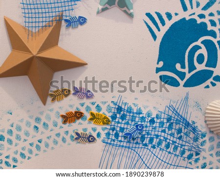 canvas with stencil printed fish drawing. Clam shells glazed with acrylic paint. Summer theme craft.