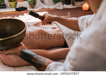 Stock photo of unrecognized man lying in the floor and receiving body massage with natural plants.