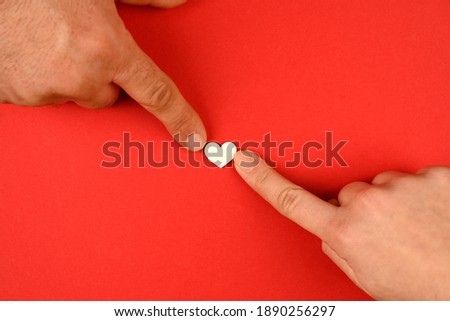 Valentine's Day background. hands of a couple giving their heart on a red background. Valentine's Day concept. Flat view, top view, copy space