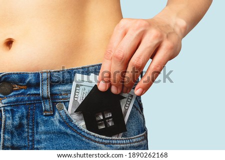 Banknotes of hundred dollars with a house symbol in the jeans pocket, soft focus background