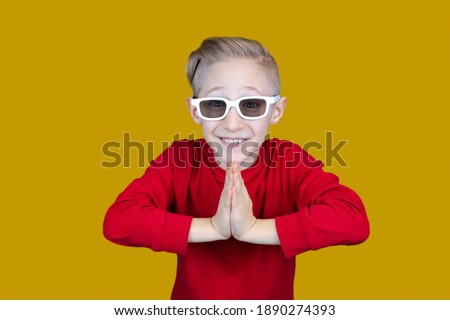 funny child in children's 3D glasses puts his hands together and laughs