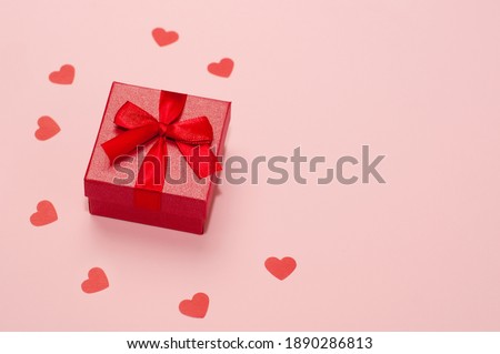 red ring box on pink background with confetti of hearts
