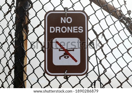 No drones warning sign on old rusty fence.  