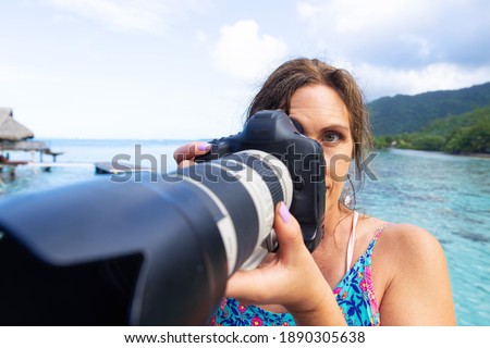 Female photographer taking a photo with long lens DSLR
