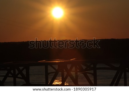 Golden sunsetting across a watery horzion with a steel bridge silhouette in the foreground