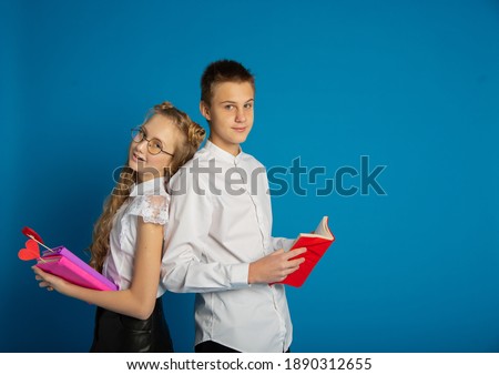 A couple of schoolchildren are teenagers on Valentine's Day on a blue background