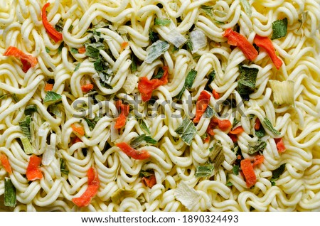 Textured background consisting of dry noodles and pieces of vegetables.