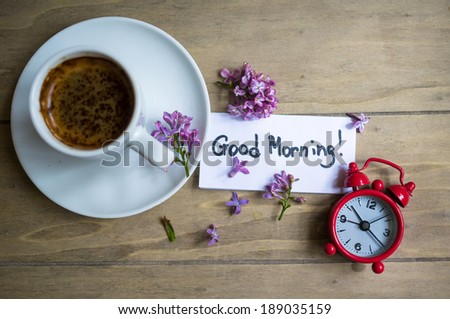 Cup of coffee, Good morning note and lilac flower on the wooden table