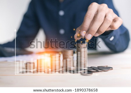businessman holding coins putting in glass. concept saving money for finance accounting to arrange coins into growing graphs concept. Royalty-Free Stock Photo #1890378658