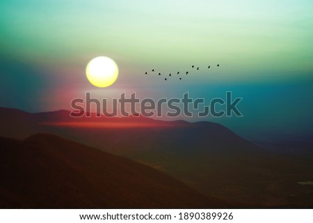 sunrise on morning sky over green mountain and silhouette bird flying on rainbow sky in Lopburi Thailand