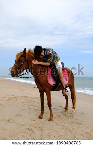 A Asian person huging the brown horse at Hua Hin beach, Prachuap Khiri Khan, Thailand.