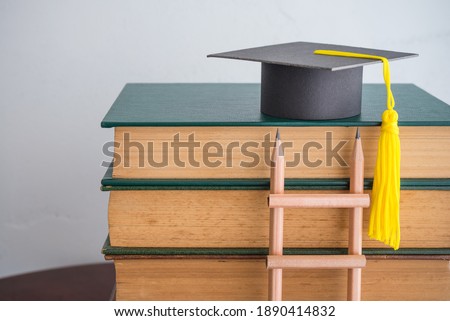 Graduation cap on textbooks with pencil ladder in classroom background copy space. Business education, abroad educational and goal or target successful graduation concept. Royalty-Free Stock Photo #1890414832