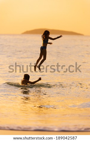 Younger girl jumping off of an older girls shoulder while swimming in Cinnamon Bay, St. John, USVI