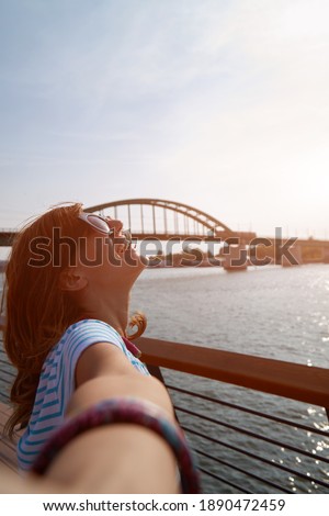 Young woman taking selfie outdoors near the river in city environment. Royalty-Free Stock Photo #1890472459