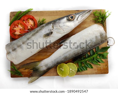 Fresh raw Barracuda Fish (cheelavu) head and tail decorated with herbs and vegetables on a White background.Selective Focus. Royalty-Free Stock Photo #1890492547