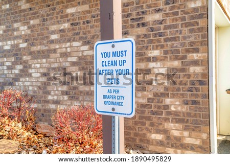You Must Clean Up After Your Pets signage with brick wall of building background