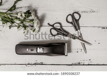 composition with hairdressing tools and flowers on a worn white wooden background. Template for a postcard or information about a hair salon.  flat lay, copy space