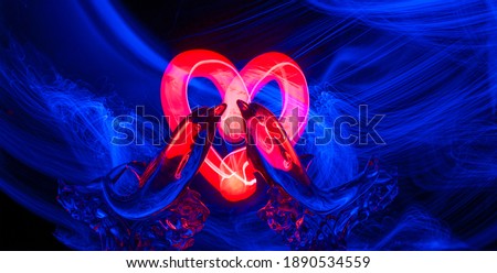 Love concept in neon light: dolphins, heart, light and colored lines.