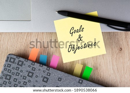 Goals and Objectives words written on note. Diary, pen and laptop. Business concept.