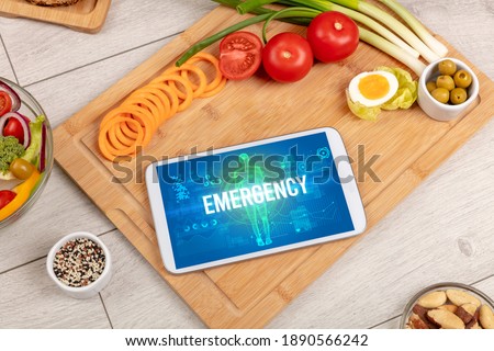 EMERGENCY concept in tablet with fruits, top view